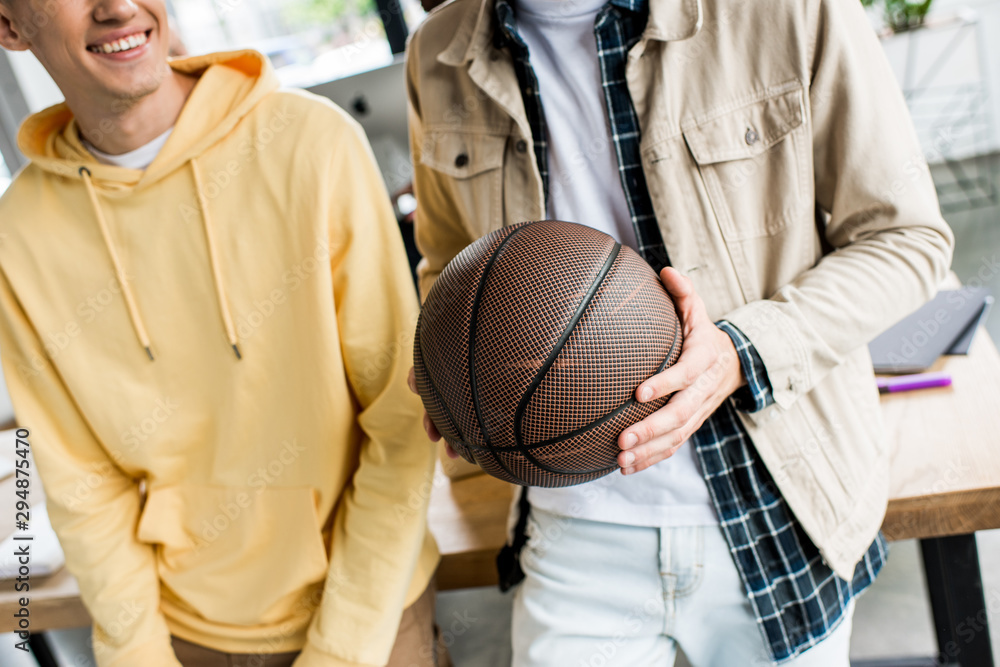 cropped view of businessman holding volleyball ball while standing near colleague in office cropped view of businessman holding volleyball ball while standing near colleague in office