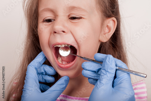 Dental medicine and healthcare - dentist examining little child girl patient open mouth showing caries teeth decay