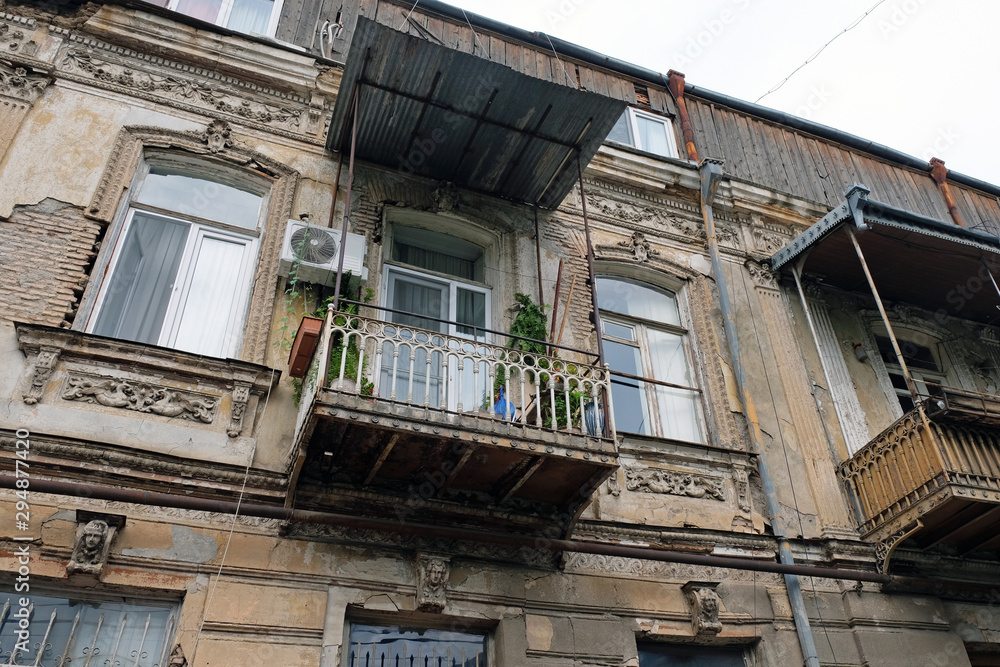 Old balconies on historic buildings in Tbilisi. View of the architecture of Georgia before reconstruction. Metal balconies with a roof in a two-story house.