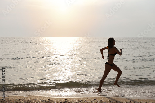 happiness on holiday silhouette side view image of young asian beautiful and sexy girl in black bikini who running on sandy beach in sunset on summer vacation
