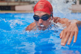 Swimmer in an outdoor pool, swimming in the crawl style, pulling the head out of the water, seen from the water level front