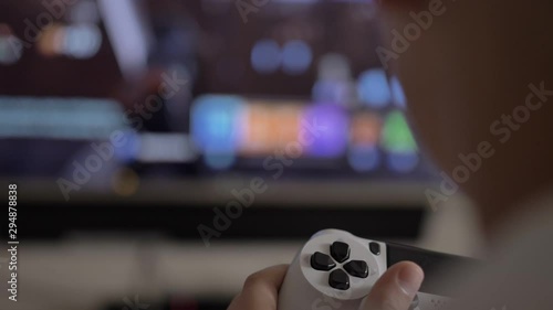 boy sits near the TV and plays in the console, joystick close-up, have fun
