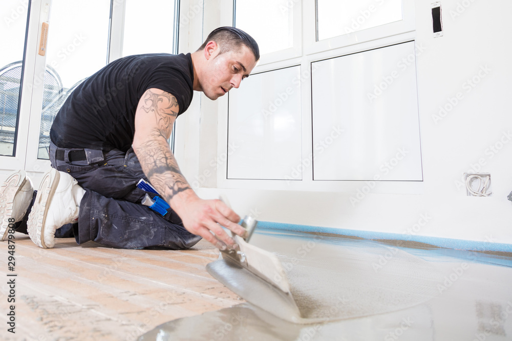 male worker working with self-levelling cement mortar during floor renovation male worker working with self-levelling cement mortar during floor renovation