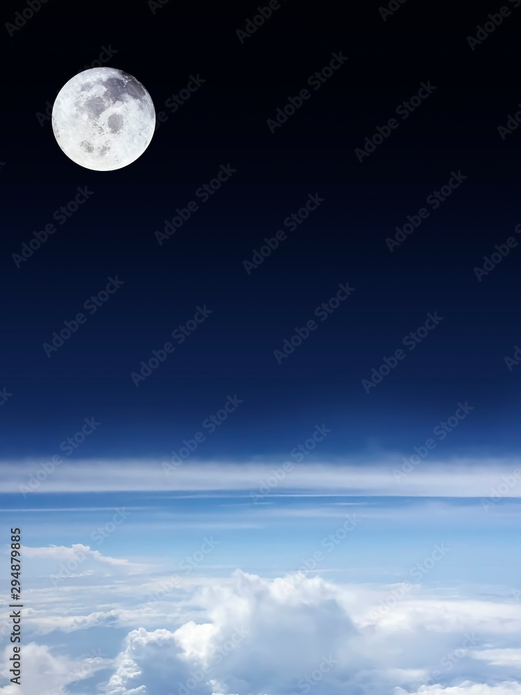 Horizontal clouds with bright blue sky below and dark space above with beautiful full moon.Image of moon furnished by NASA.