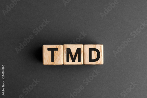 TMD - acronym from wooden blocks with letters, abbreviation TMJ temporomandibular joint syndrome, TMD Temporomandibular disorder concept, gray background photo