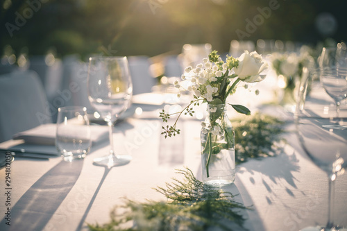 Fototapeta Beautiful outdoor table setting with white flowers for a dinner, wedding reception or other festive event