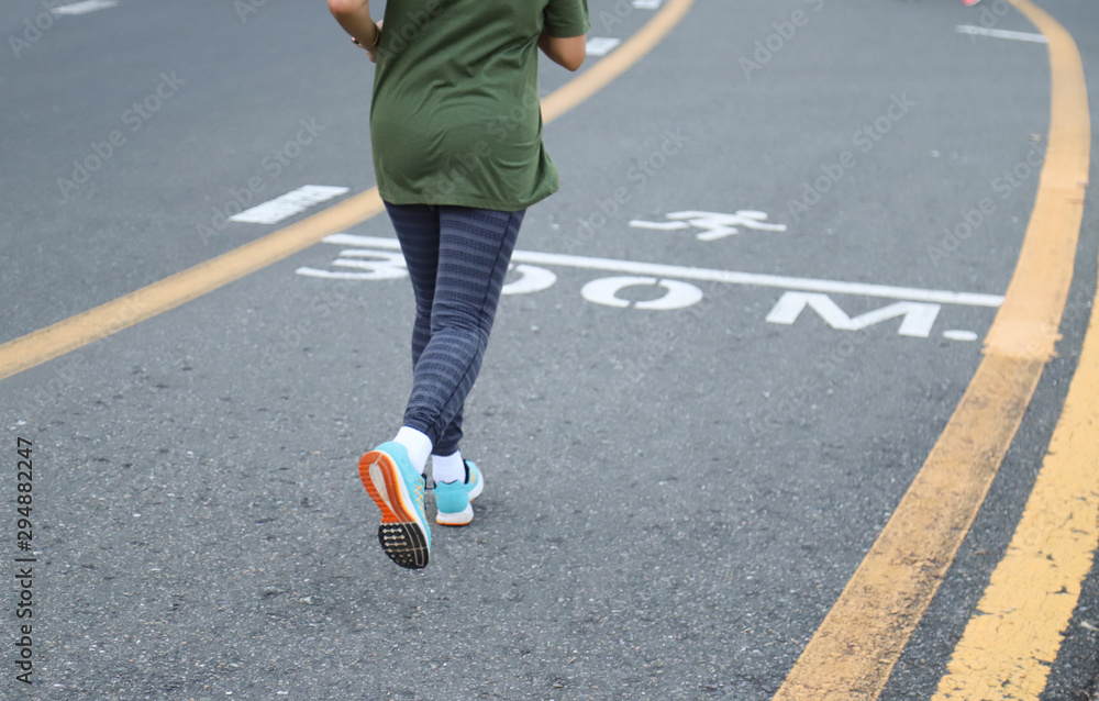 Closeup of Asian woman jogging in the track on the road of public park in the evening.