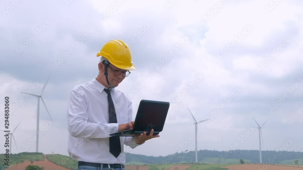 Engineer at windmill power plant with notebook computer in hand Engineer at windmill power plant with notebook computer in hand