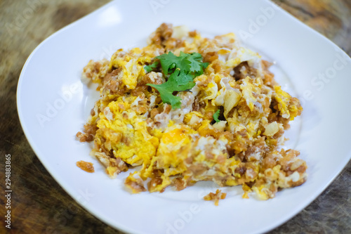 Stir fried pickle turnip with egg in white plate on wooden table, Thai food.
