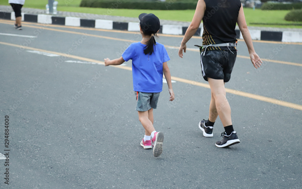 Closeup of Asian man and girl walking together in jogging track on the street. Lovely and healthy family activity. 