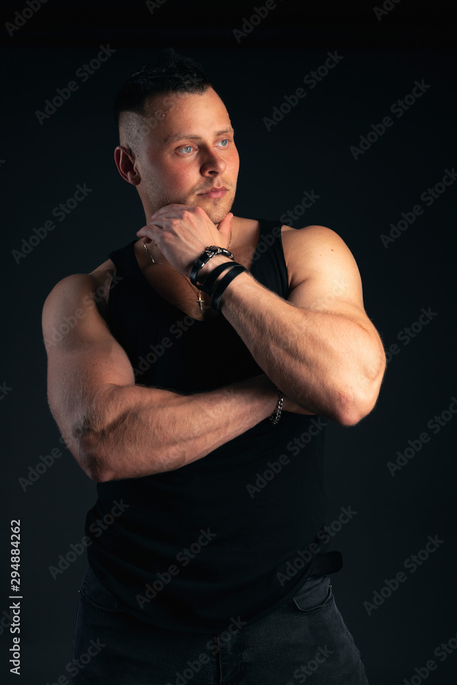 Strong and handsome young man with muscles and biceps. Studio shooting on black background.