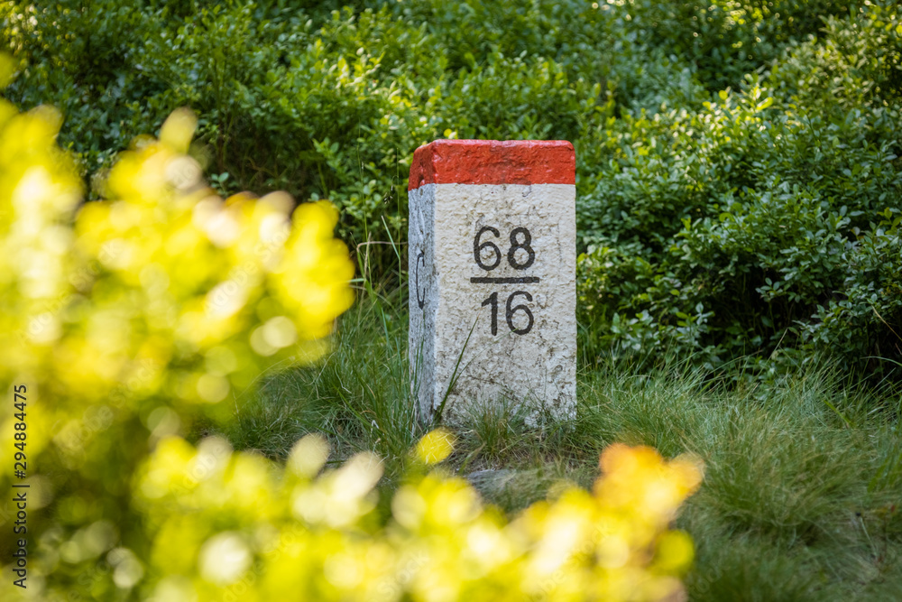 Czech border pillar red and white color, at the boundary of Poland and Czech Republic. Forest scene.