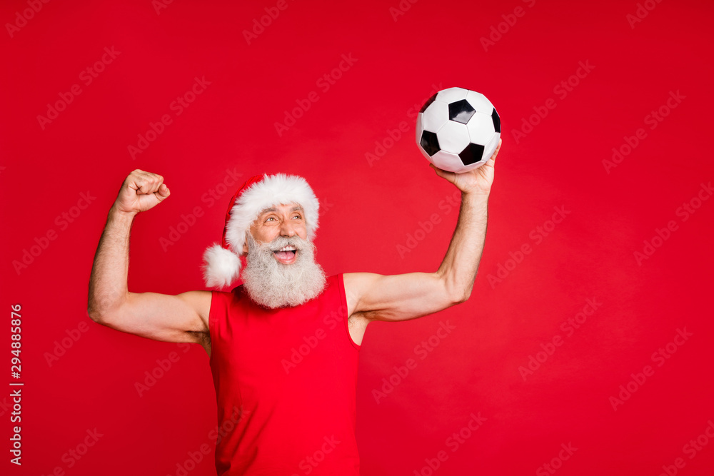 Portrait of crazy santa claus in nicholas hat cap screaming yes raising fists see goal in match wearing sports wear isolated over red background Portrait of crazy santa claus in nicholas hat cap screaming yes raising fists see goal in match wearing sports wear isolated over red background