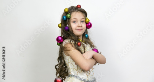 Girl with New Year's toys on a white background. A little girl with Christmas balls decorated her hair on her head.