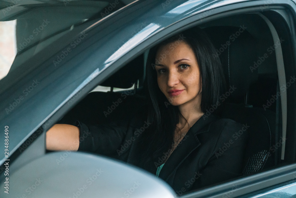 Woman wearing smart casual wear sits in car interior