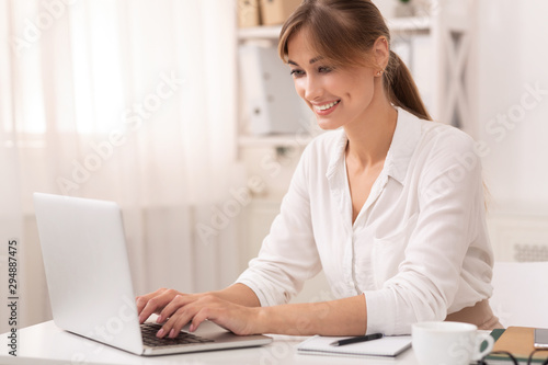 Smiling Businesswoman Using Laptop Working In Office