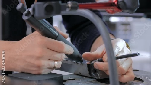 Professional male welder trying to work with gas tungsten arc welding GTAW or tungsten inert gas TIG technology at exhibition or trade show - close up view. Industrial concept and engineering work