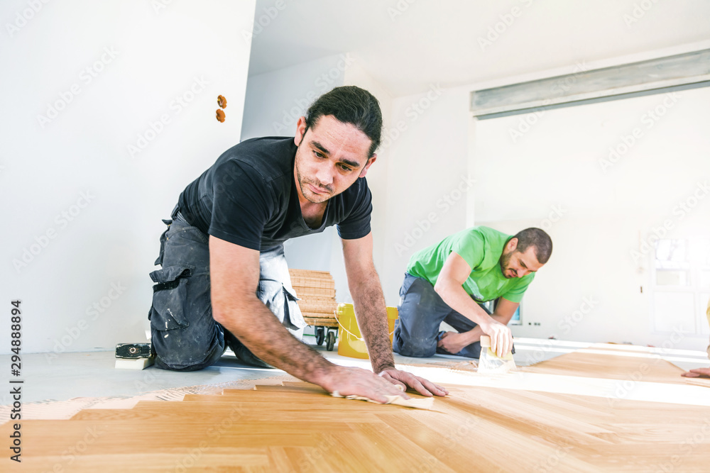 Handwerker verlegen Fischgrat Parkett in einer luxuriöser Wohnung Handwerker verlegen Fischgrat Parkett in einer luxuriöser Wohnung