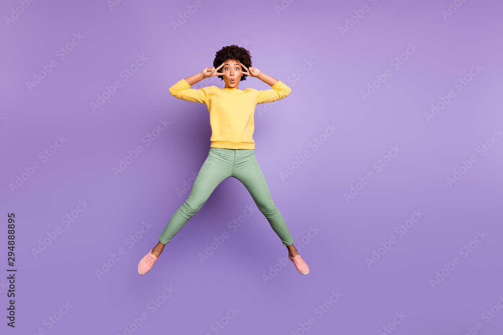 Full size photo of funky funny brunette curly hair girl jump make v-signs near her face wear casual style clothing sneakers isolated violet color background