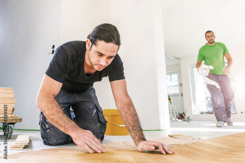 Handwerker verlegen Fischgrat Parkett in einer luxuriöser Wohnung Handwerker verlegen Fischgrat Parkett in einer luxuriöser Wohnung