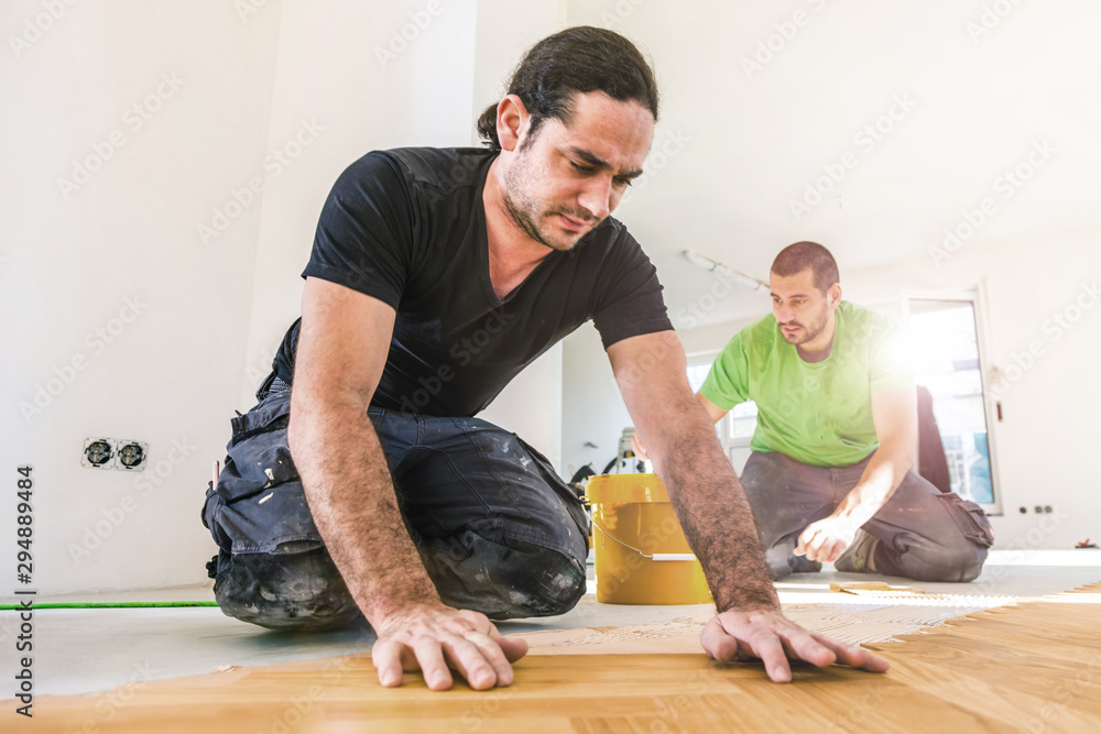 Carpenter on work putting wood parquet pieces. Home construction Carpenter on work putting wood parquet pieces. Home construction