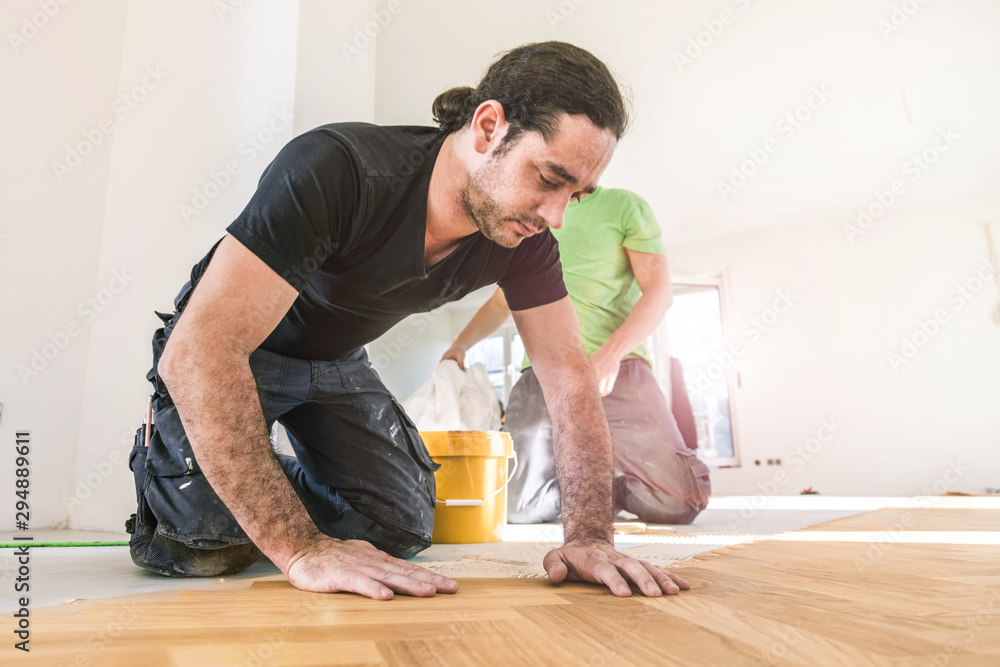 Carpenter on work putting wood parquet pieces. Home construction Carpenter on work putting wood parquet pieces. Home construction