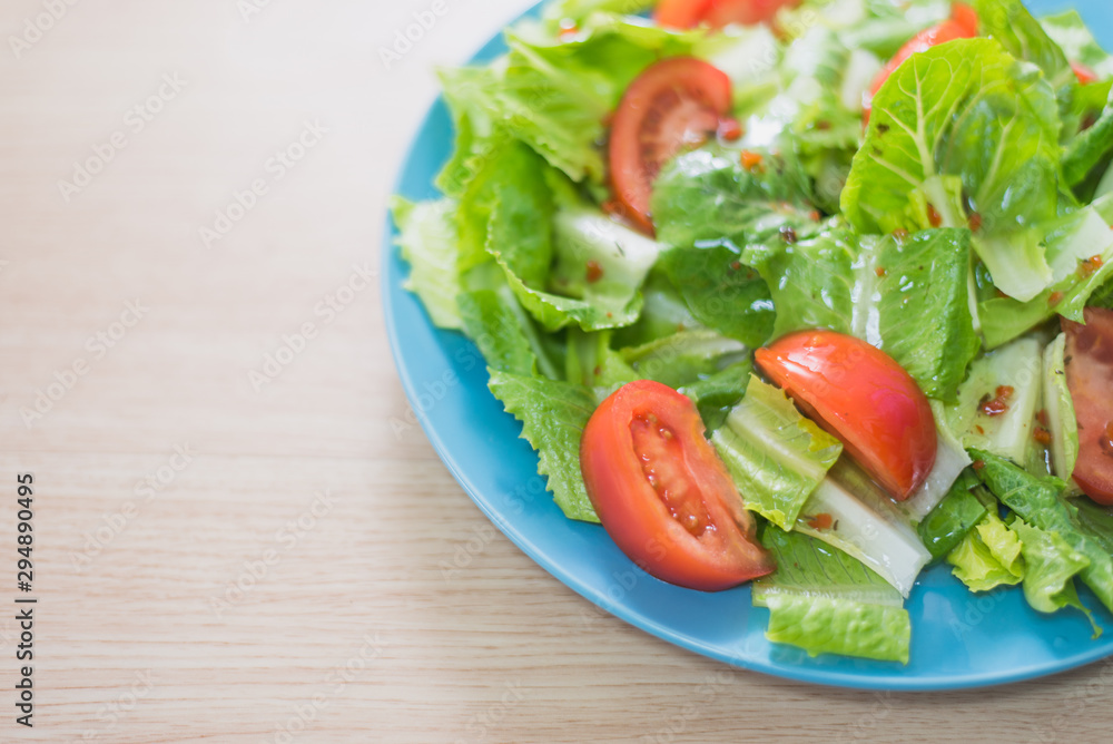 Delicious and healthy fresh organic tomato and romaine lettuce salad with vinaigrette dressing sauce on a wooden surface Delicious and healthy fresh organic tomato and romaine lettuce salad with vinaigrette dressing sauce on a wooden surface