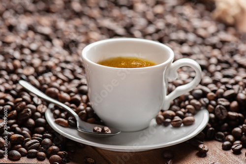 Cup of coffee with coffee beans with out of focus background all resting on a table