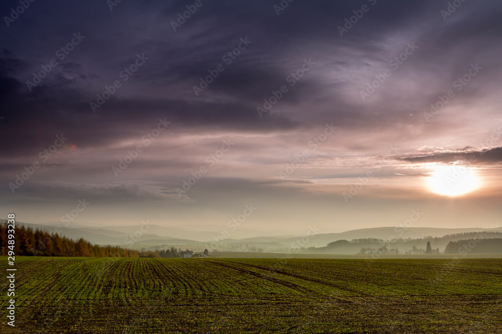 View of the Ore Mountains in autuum, foggy meadow in the background and forests, dark clouds and sunset, View of the Ore Mountains, Germany