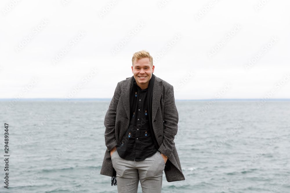 Smiling man wearing gray coat by Vattern lake in Stora Lund Nature Reserve, Sweden Smiling man wearing gray coat by Vattern lake in Stora Lund Nature Reserve, Sweden