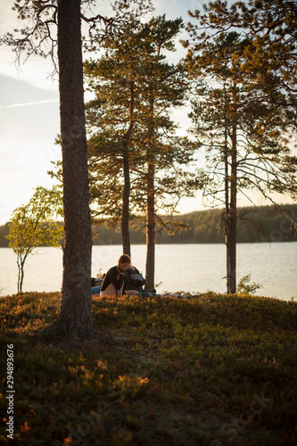 Young woman reading at sunset by Lake Norra Bredsjon, Sweden photo