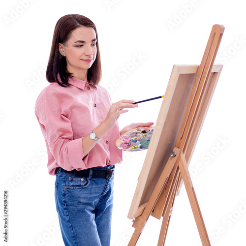 portrait of young woman artist with easel, palette and paint brush painting picture isolated on white