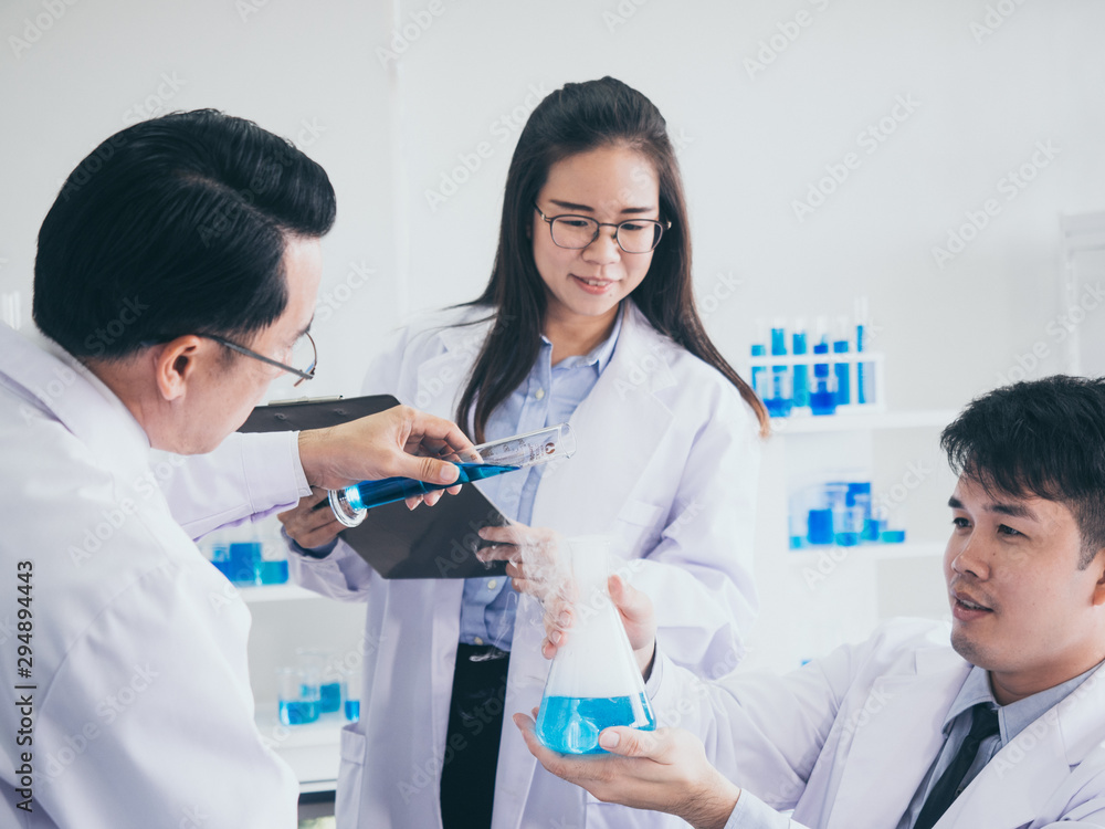 Scientists pour blue liquid into glass in a science laboratory. Scientists pour blue liquid into glass in a science laboratory.