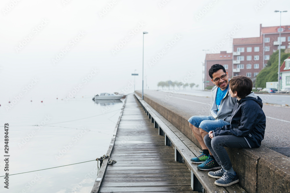 Father and son sitting by harbour Father and son sitting by harbour