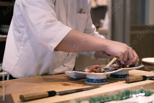 Fotografie Chef preparing sashimi dish at his counter, Omakase style Japanese traditional restaurant
