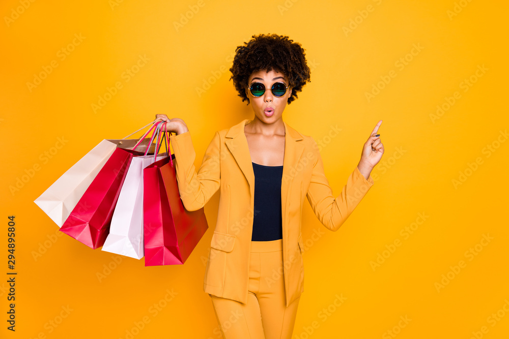 Look unbelievable sale. Amazed brunette wavy hair girl point index finger copyspace while shopping follow discounts on autumn hold bags wear jacket trousers isolated yellow color background Look unbelievable sale. Amazed brunette wavy hair girl point index finger copyspace while shopping follow discounts on autumn hold bags wear jacket trousers isolated yellow color background