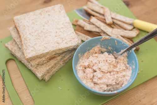 Preparing a tuna mayo sandwich on a chopping board. Wheat bread and tuna mayonnaise ready on the chopping board.