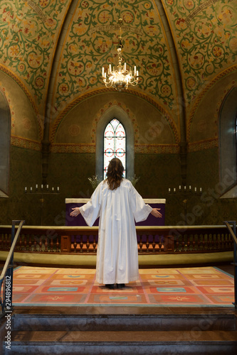 Priest in white robes standing at chancel in church