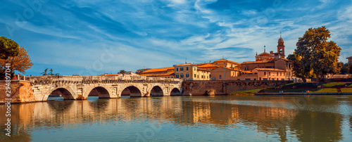 Tiberius bridge in Rimini on a background of blue sky with white clouds