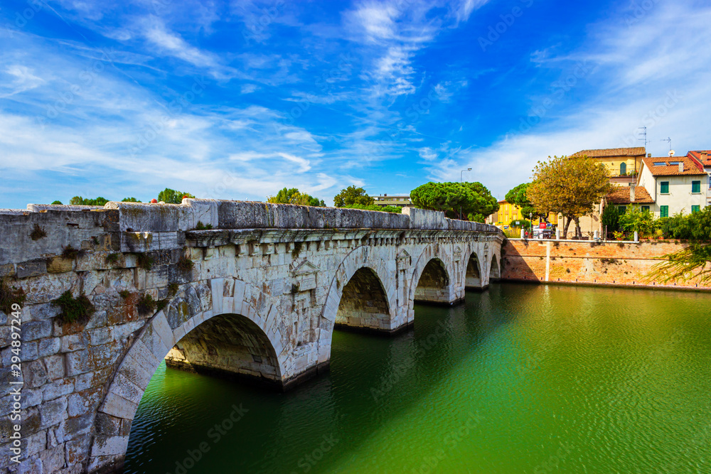 Tiberius bridge in Rimini on a background of blue sky with white clouds