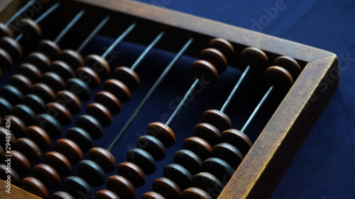 Vintage wooden abacus close up. Counting wooden knuckles. Part of the old end of the abacus on a dark blue background.
