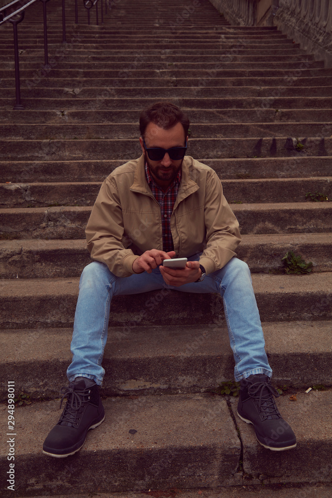 Handsome man sitting on stairs and using cellphone. Handsome man sitting on stairs and using cellphone.