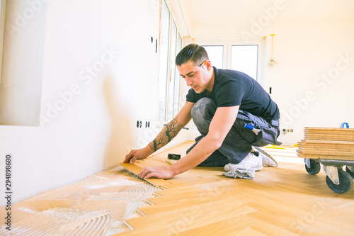 Handwerker bei der arbeit, fischgrät parkett verlegen ,sockelleisten montage . photo