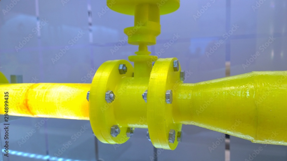Flange connection of pipes with bolts and nuts with hexagonal heads. Layout of the pipeline made of yellow plastic material.  Exposition in international Gas and technology forum and exhibition.