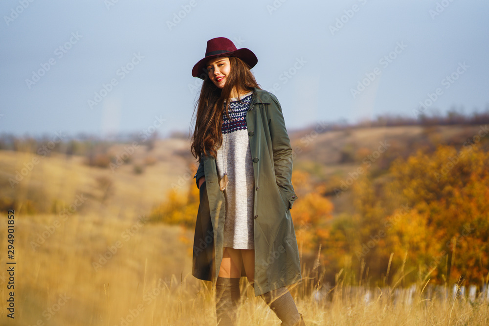 Beautiful young stylish girl in a coat walks in the autumn in the park. The girl is dressed in a green coat and a red hat. Beautiful evening. Autumn fashion. Lifestyle. High fashion portrait. Beautiful young stylish girl in a coat walks in the autumn in the park. The girl is dressed in a green coat and a red hat. Beautiful evening. Autumn fashion. Lifestyle. High fashion portrait.