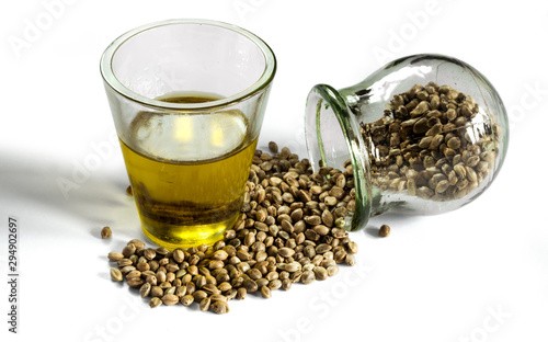 Hemp seeds in a jar and hempseed oil in a measuring glass beaker isolated on a white background.