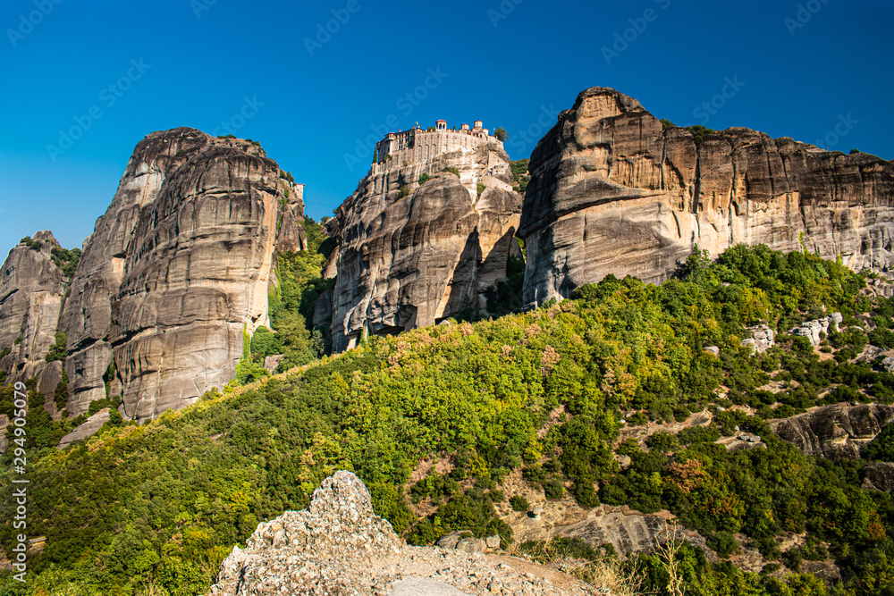 Monastery Meteora Greece. Stunning  panoramic landscape. View of mountains and green forest against epic blue sky with clouds. UNESCO heritage object.