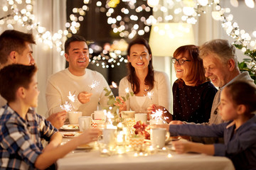 celebration, holidays and people concept - happy family with sparklers having tea party at home