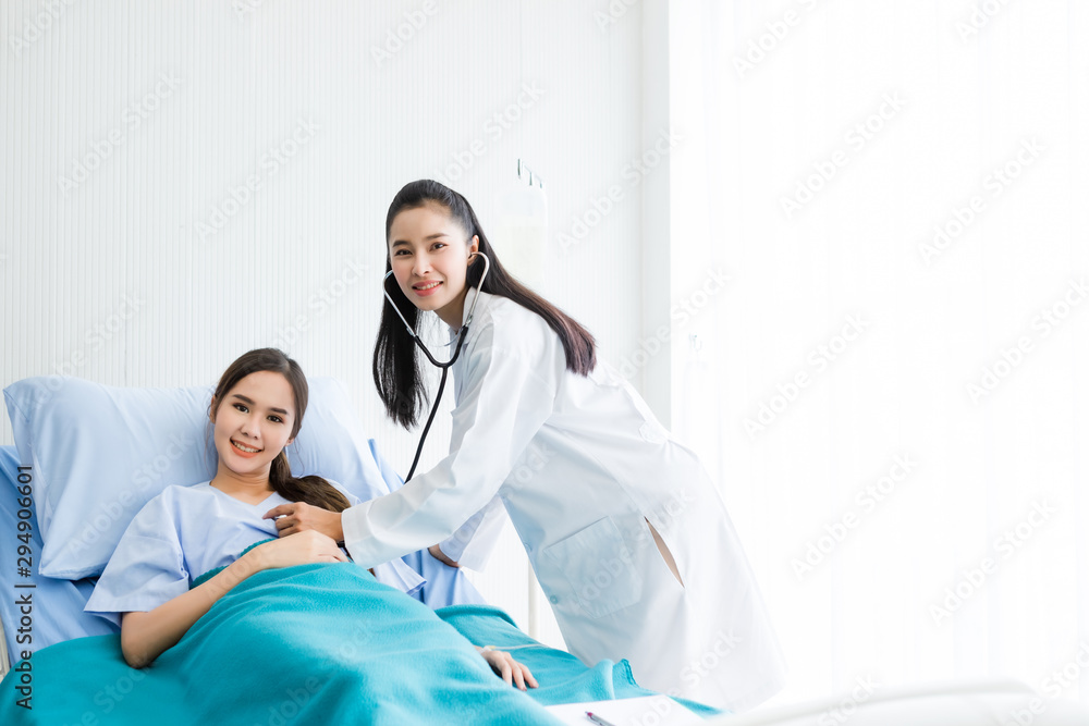 Obraz premium Asian young female patient on bed while doctor hands of checking examining his pulse for record the treatment results with smiley face very good symptom in hospital background.