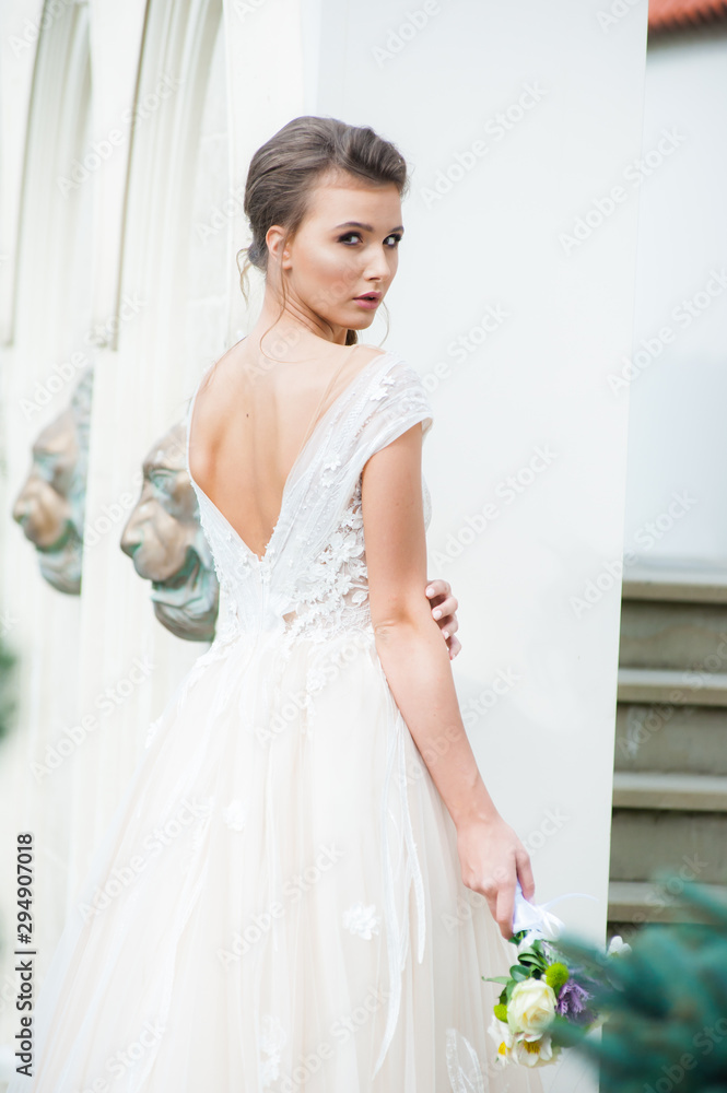 Beautiful bride with wedding flowers bouquet, attractive woman in wedding dress. Happy newlywed woman. Bride with wedding makeup and hairstyle. Smiling bride. Wedding day. Gorgeous bride. Marriage.
